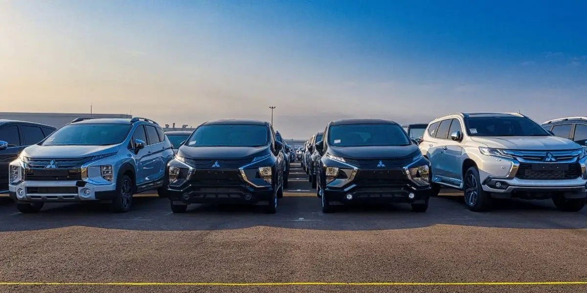 Row of parked cars lined up in an outdoor lot under a bright blue sky